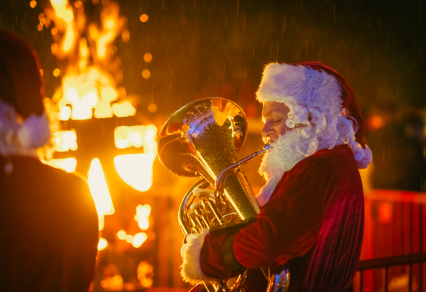 Kerstman speelt muziek op de kerstmarkt.